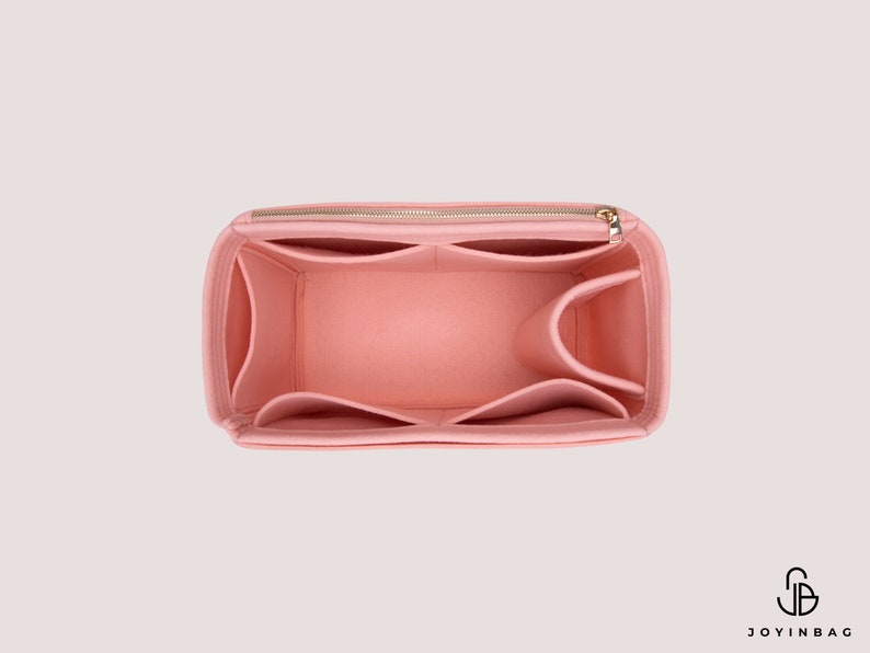 K&ouml;nnte beinhalten: Ein rosa Filztaschenorganizer mit mehreren F&auml;chern und einem Rei&szlig;verschluss. Der Organizer ist so konzipiert, dass er in eine gr&ouml;&szlig;ere Tasche passt und hilft, sie zu organisieren.