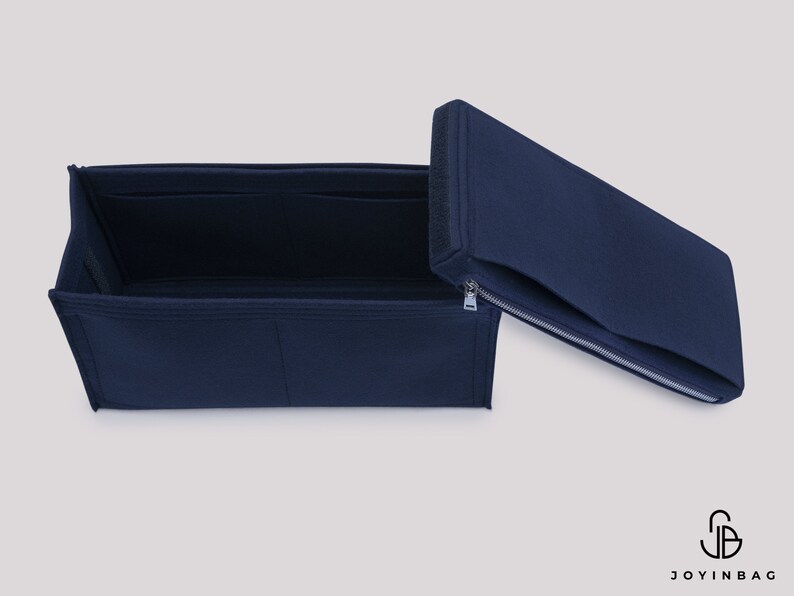 May include: A navy blue felt bag organizer with multiple compartments and a zippered top. The organizer is open and the top is folded back.