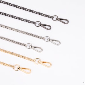 May include: Four different chain straps with lobster clasps. The chains are silver, gold, and two shades of gunmetal.
