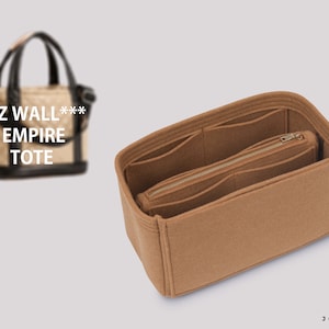 May include: A tan felt handbag organiser with multiple compartments and a zipped pocket. The organiser is designed to fit inside a tote bag. The text "MZ WALL*** EMPIRE TOTE" is visible on a blurred handbag in the background.