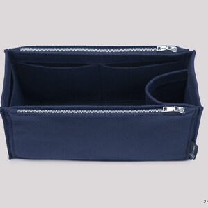 May include: A navy blue felt bag organiser with multiple compartments and a zipper closure. The organiser is designed to fit inside a larger bag.