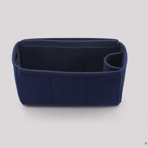 May include: A dark blue felt bag organizer with multiple compartments and a zippered pocket. The organizer is designed to fit inside a larger bag and help keep it organized.