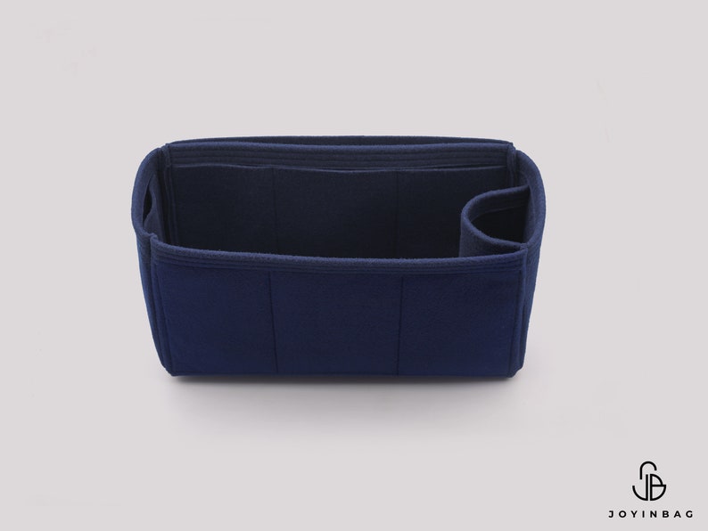 May include: A dark blue felt bag organizer with multiple compartments and a zippered pocket. The organizer is designed to fit inside a larger bag and help keep it organized.