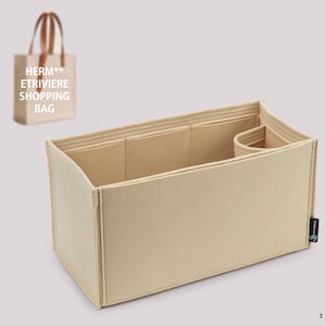 Puede incluir: Organizador de bolso de mano de fieltro beige con múltiples compartimentos. El organizador tiene forma rectangular con un lado curvo y un pequeño bolsillo separado. En el fondo hay un pequeño bolso tote con el texto "HERM** ETRIERE SHOPPING BAG".