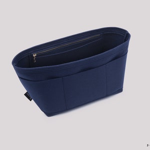 May include: A navy blue felt bag organiser with multiple pockets and a zipped compartment. The organiser is designed to fit inside a larger bag and help keep it organised.