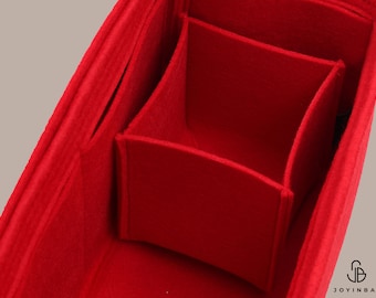 May include: Red felt bag organizer with multiple compartments. The organizer has a rectangular shape and is divided into several sections. The felt is soft and plush.