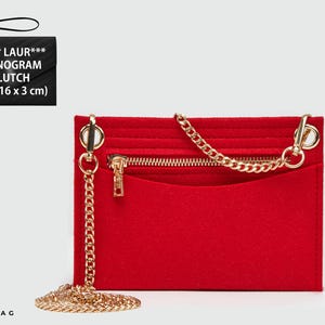 May include: A bright red felt bag organiser insert featuring a gold-toned metal chain strap, a horizontal zippered pocket, and an open slip pocket. The rectangular accessory measures 21 x 16 x 3 cm and includes a detachable wrist strap for versatility.