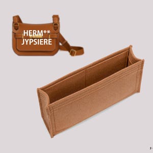 Puede incluir: Un inserto de bolsa de fieltro marrón con múltiples compartimentos. El inserto está diseñado para adaptarse a un bolso de mano específico. El inserto tiene el texto "HERM** JYPSSIER" impreso en él.