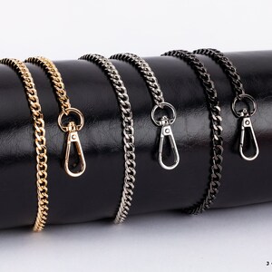 May include: Four different chain bag straps with lobster clasps. The chains are gold, silver, black, and gunmetal.