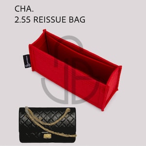 以下が含まれることがあります： 「CHA. 2.55 REISSUE BAG」の文字が入った鮮やかな赤色のバッグオーガナイザーが、ゴールドチェーンストラップ付きの黒いキルティングハンドバッグの隣に表示されています。 オーガナイザーは長方形で、2つのコンパートメントがあります。