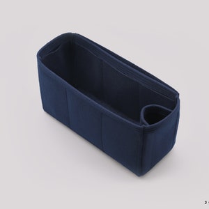 May include: A dark blue felt bag organizer with multiple compartments and a small pocket. The organizer is designed to fit inside a larger bag, helping to keep items organized.