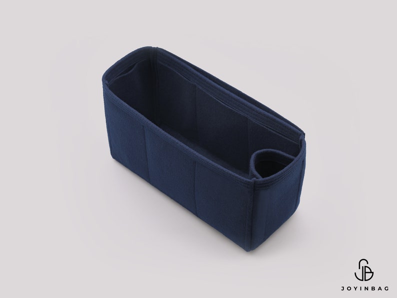May include: A dark blue felt bag organizer with multiple compartments and a small pocket. The organizer is designed to fit inside a larger bag, helping to keep items organized.