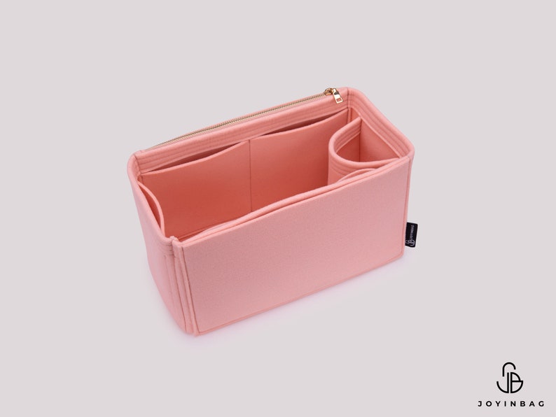 K&ouml;nnte beinhalten: Ein rosa Filztaschenorganizer mit mehreren F&auml;chern und einem Rei&szlig;verschluss. Der Organizer ist so konzipiert, dass er in eine gr&ouml;&szlig;ere Tasche passt und hilft, sie zu organisieren.