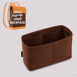 Puede incluir: Un organizador de bolso de fieltro marrón con múltiples compartimentos interiores y forma rectangular. Al fondo, se ve una mochila marrón y naranja con el texto LOUI* VUI**** SOHO BACKPACK impreso encima.