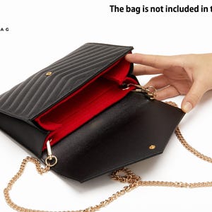May include: A black quilted handbag insert with a vibrant red interior lining. The insert features a structured design with open compartments and gold-toned metal chain attachments. The text "The bag is not included in the sale" is visible.