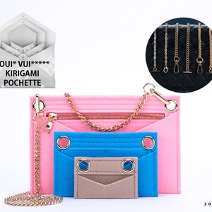 May include: A pink felt pouch with a zipper closure and a gold chain strap. The pouch has three compartments, one pink, one blue, and one beige. The pouch is labeled "LOUI*VUI****** KIRIGAMI POCHETTE".