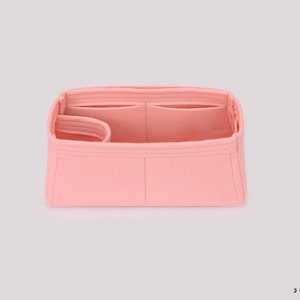 May include: A pink felt bag organizer with multiple compartments and a zippered pocket. The organizer is designed to fit inside a larger bag and help keep it organized.