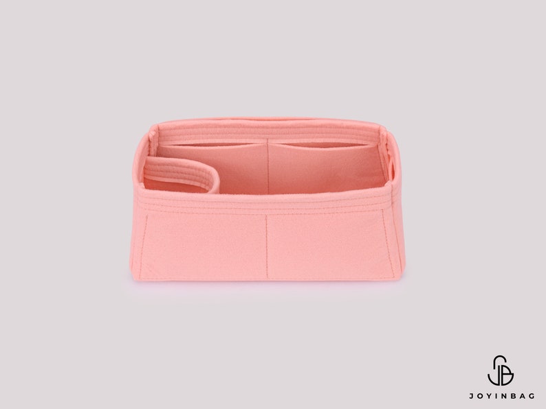 May include: A pink felt bag organizer with multiple compartments and a zippered pocket. The organizer is designed to fit inside a larger bag and help keep it organized.