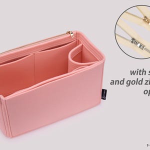 K&ouml;nnte beinhalten: Rosa Filztasche Organizer mit mehreren F&auml;chern und Rei&szlig;verschluss. Der Taschenorganizer ist ge&ouml;ffnet und leer dargestellt. Das Bild zeigt auch eine Nahaufnahme eines silbernen und goldenen Rei&szlig;verschlusses.