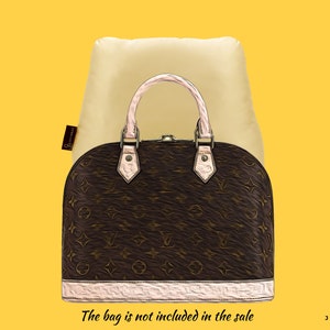 Könnte beinhalten: Ein beiger Staubbeutel mit einer braunen und beigen Handtasche mit einem rosafarbenen Henkel. Die Tasche hat ein braunes und beiges Monogrammbild. Der Text "The bag is not included in the sale" befindet sich am unteren Rand des Bildes.