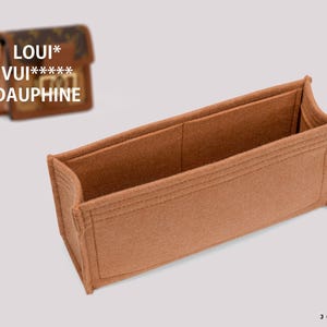 May include: A rectangular brown felt handbag organiser insert with stitched seams and an open top. In the background, a small brown patterned handbag is visible with the text LOUI* VUI***** DAUPHINE printed over it, and a logo for JOYINBAG.