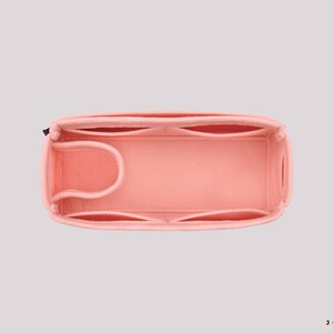 May include: A pink felt bag organizer with multiple compartments and a zipper closure. The organizer is designed to fit inside a larger bag and help keep it organized.