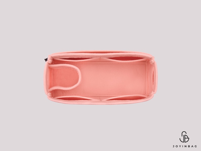 May include: A pink felt bag organizer with multiple compartments and a zipper closure. The organizer is designed to fit inside a larger bag and help keep it organized.