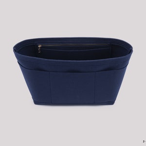May include: A navy blue felt bag organiser with multiple pockets and a zipped compartment. The organiser is designed to fit inside a larger bag.