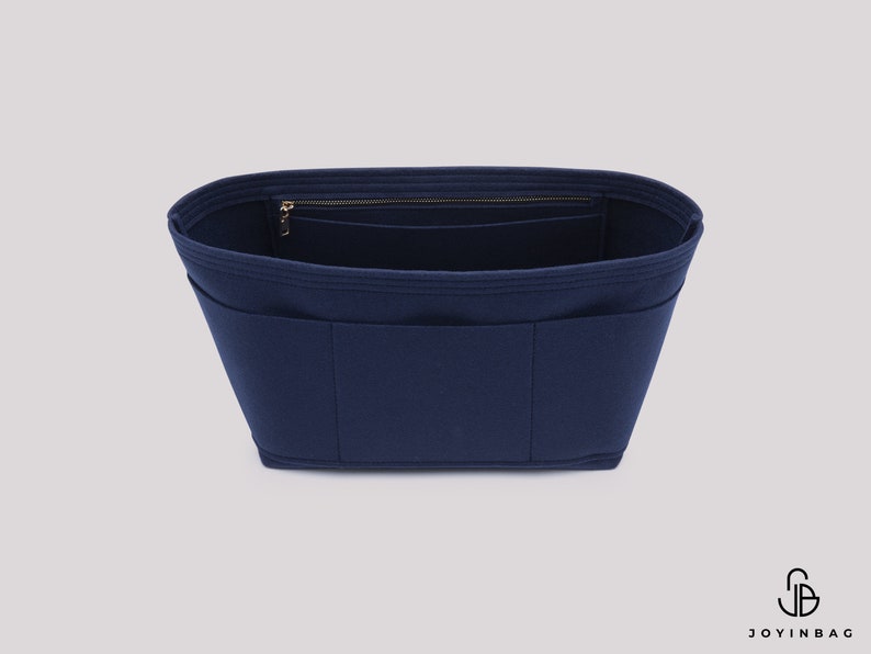 May include: A navy blue felt bag organiser with multiple pockets and a zipped compartment. The organiser is designed to fit inside a larger bag.