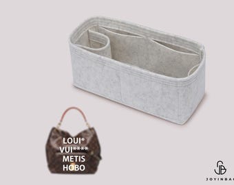 Puede incluir: Un organizador de bolso de fieltro gris con varios compartimentos. El organizador está diseñado para caber dentro de un bolso Louis Vuitton Metis Hobo.