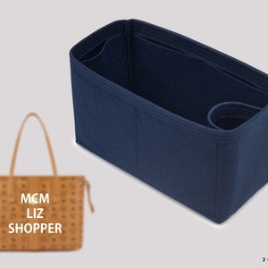 May include: A navy blue felt bag organizer with multiple compartments and a handle. The organizer is designed to fit inside a brown leather tote bag with the text "MCM Liz Shopper" printed on the front.