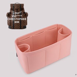 Puede incluir: Un organizador de bolso de fieltro rosa con múltiples compartimentos y bolsillos. El organizador está diseñado para caber dentro de una mochila Louis Vuitton Christopher MM.