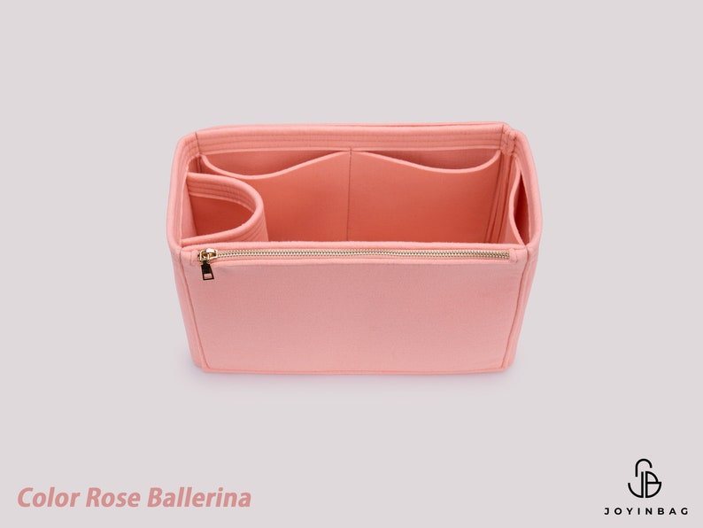 K&ouml;nnte beinhalten: Ein rosa Filz-Taschenorganizer mit mehreren F&auml;chern und einem Rei&szlig;verschluss. Die Tasche ist offen und das Innere ist sichtbar. Der Text "Color Rose Ballerina" ist unten im Bild zu sehen.