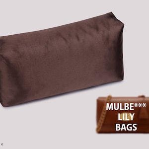 Op de afbeelding: Een bruine fluwelen etui met een zwart logo met de tekst "Joyinbag". Het etui ligt op een witte achtergrond. Onder het etui ligt een bruine leren handtas met een gouden kettingband. De handtas heeft de tekst "Mulbe*** Lily Bags" op de voorkant.