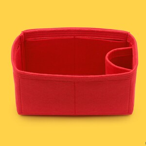 May include: Red felt bag insert with multiple compartments and a single large pocket. The insert is designed to fit inside a handbag.