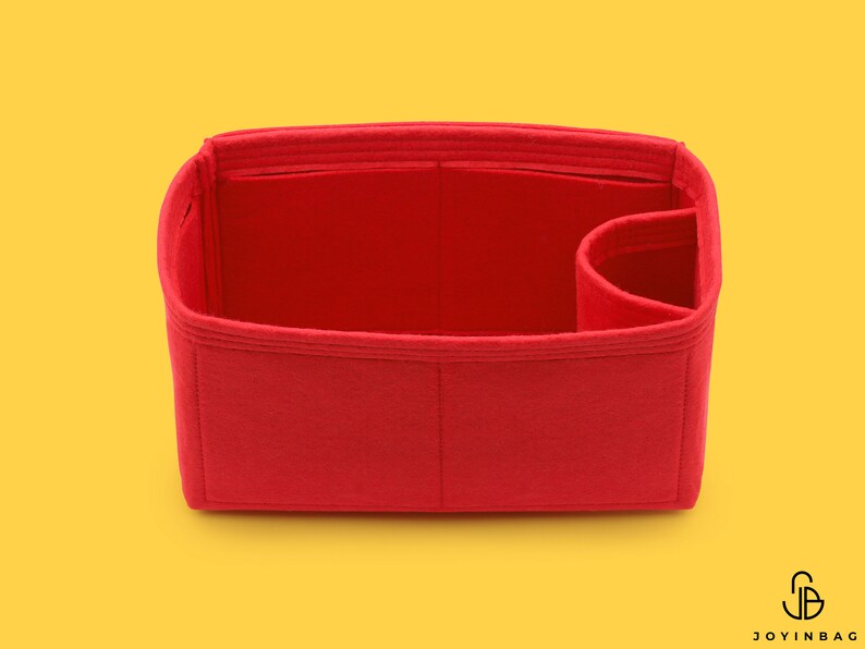 May include: Red felt bag insert with multiple compartments and a single large pocket. The insert is designed to fit inside a handbag.