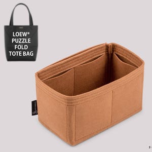 Pode incluir: Um organizador de bolsa em feltro castanho-claro com múltiplos compartimentos interiores e uma etiqueta lateral preta. No canto superior esquerdo, uma bolsa tote preta exibe o texto LOEW* PUZZLE FOLD TOTE BAG. O logótipo JOYINBAG está no canto inferior direito.