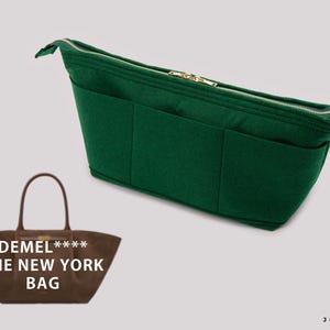 Könnte beinhalten: Ein dunkelgrüner Handtaschen-Organizer aus Filz mit mehreren Außentaschen und einem goldfarbenen Reißverschluss, abgebildet neben einer braunen Tragetasche mit der Aufschrift DEMEL**** THE NEW YORK BAG und einem Logo mit dem Text JOYINBAG.