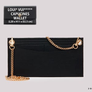 Op de afbeelding: Zwarte leren portemonnee met een gouden ketting en een gouden sluiting. De portemonnee heeft meerdere kaartsleuven en een vak voor contant geld. De tekst "LOUI* VUI***** CAPUCINES WALLET (L20 x H11 x D2.5 cm)" staat op de voorkant van de portemonnee.