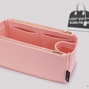 May include: Pink felt bag organizer with multiple compartments and a zipper closure. The organizer is designed to fit inside a Louis Vuitton Alma PM or MM handbag. The text "LOUIS*VUI***** ALMA PM - MM" is visible in the background.