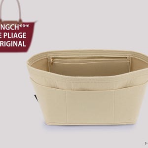 Puede incluir: Un organizador de bolso de fieltro beige con múltiples bolsillos interiores y un compartimento con cremallera. El inserto está diseñado para un bolso tote Longch*** Le Pliage Original, mostrado como un pequeño gráfico en la esquina superior.