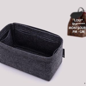 Könnte beinhalten: Ein dunkelgrauer Taschenorganizer aus Filz mit mehreren Innentaschen und rechteckiger Form. An der Seite befindet sich ein kleines schwarzes Etikett mit weißem Text. Im Hintergrund ist ein brauner Rucksack mit Muster und dem Text LOUI* VUI***** MONTSOURIS PM - GM zu sehen.