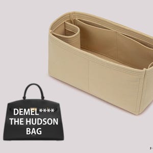 May include: Beige felt bag organizer with multiple compartments. The organizer is designed to fit inside a handbag. The text "DEMEL*** THE HUDSON BAG" is printed on a black handbag.
