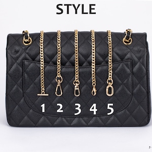 May include: A black quilted handbag with five different gold chain styles attached to the top. The chains are numbered 1 through 5.