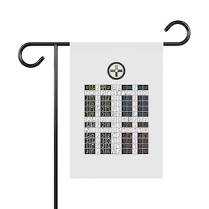 May include: A white rectangular garden flag hanging on a black metal stand. The flag features a circular emblem with a cross at the top, followed by a grid of black and white squares containing various colorful, stylized symbols and characters.