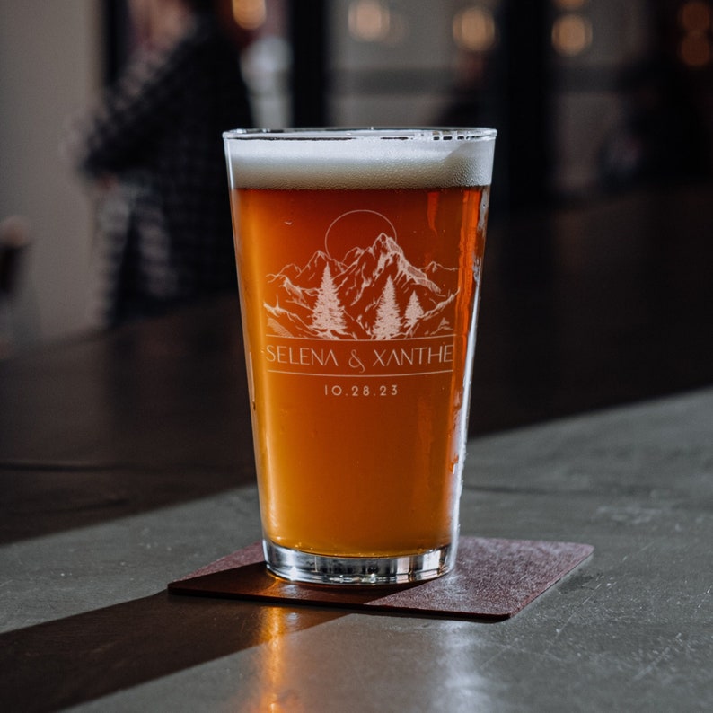 16oz beer glass laser etched with a modern forest design and personalized with names and a date.