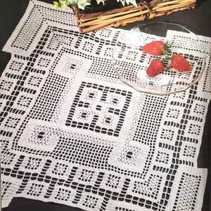 May include: White crocheted table runner with a geometric pattern. The runner is laid out on a dark surface with a glass plate and three red strawberries on top.