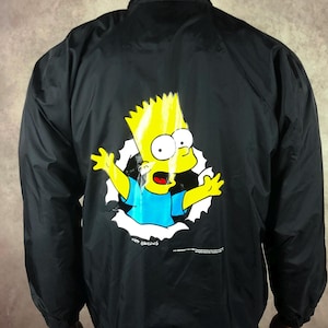 May include: Black nylon jacket with a Bart Simpson graphic on the back. The cartoon character is bursting through a torn hole. The jacket has a button-up front and a black Stone Island baseball cap.