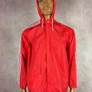 May include: A red hooded jacket with white stripes down the sleeves. The jacket has a zipper closure and a drawstring hood. The jacket is displayed on a mannequin.