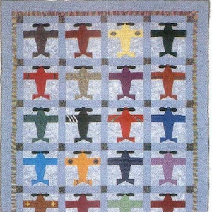 May include: A quilt with a patchwork design featuring a variety of colored airplanes. The airplanes are all the same shape but are different colors, including red, blue, green, yellow, and purple.